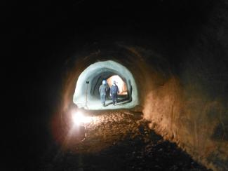 Zwei Menschen laufen in einen ausgeleuchteten Tunnel